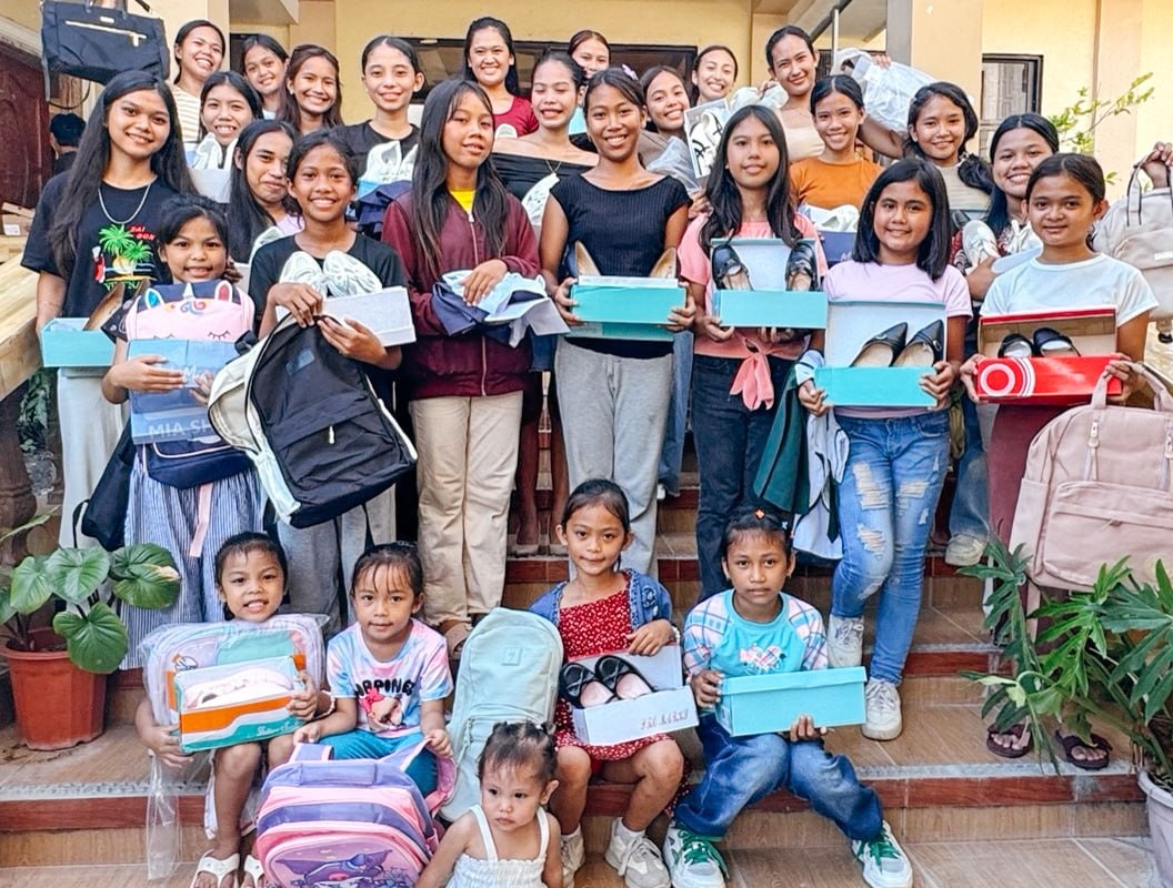 Girls at the Cebu Children’s Hope Center hold back-to-school clothes and supplies.